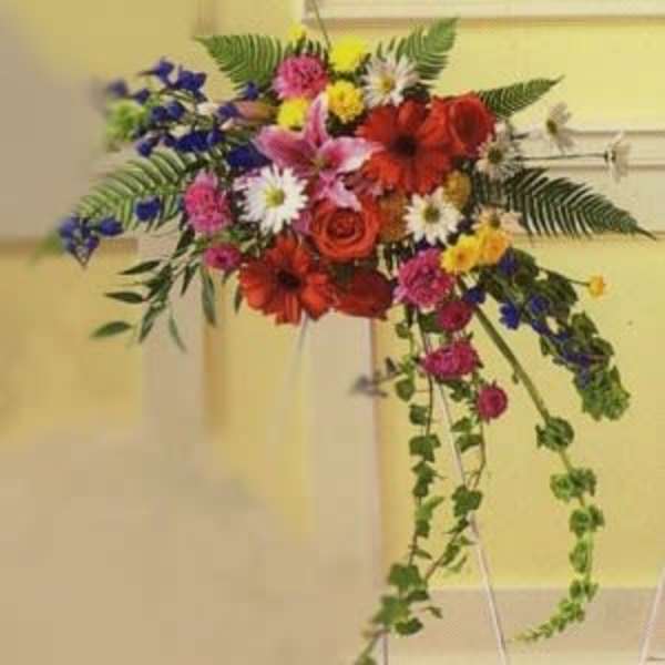 Colorful floral spray on a stand with trailing greenery.