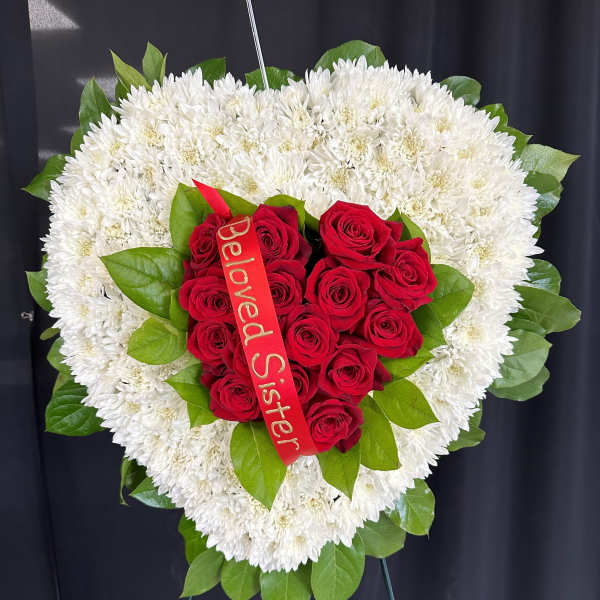 Heart-shaped white chrysanthemum wreath with red roses and a ribbon