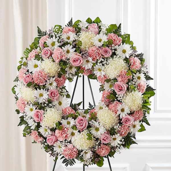 Pink and white floral wreath on a black stand
