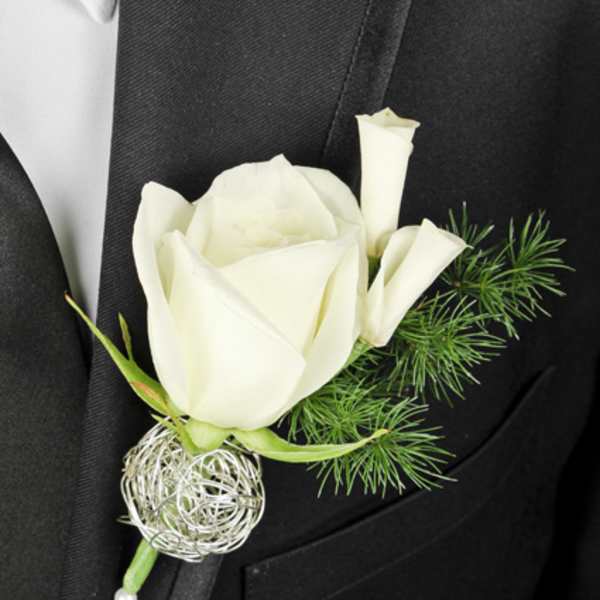 White rose boutonniere with green accents on a black suit lapel
