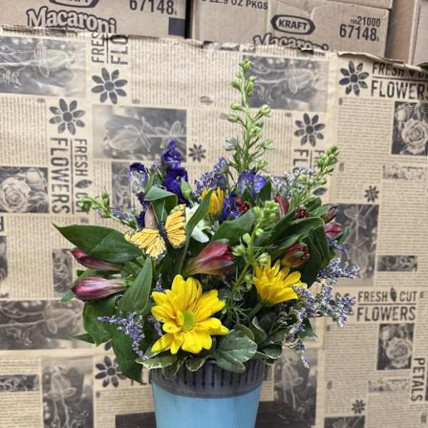 Mixed bouquet in a blue pot with yellow daisies and purple blooms
