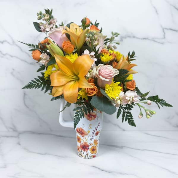 Bouquet of orange lilies, roses, and yellow mums in a floral pitcher vase