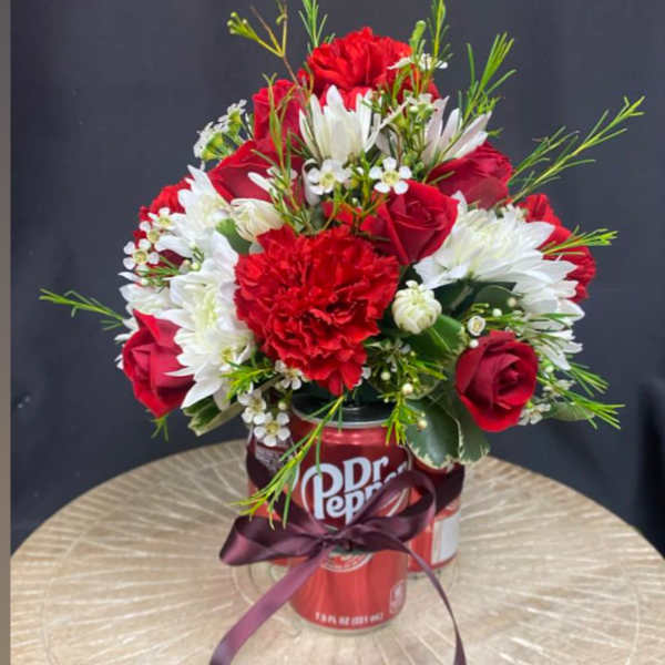 Red and white flower arrangement in a Dr Pepper can with a ribbon