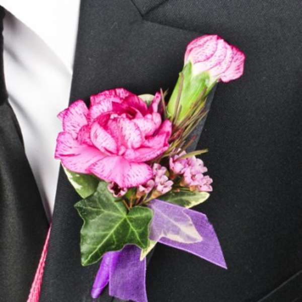 Pink boutonniere with ribbon on a black suit lapel