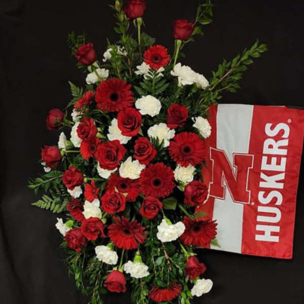 Red and white floral standing spray with a Nebraska Huskers flag