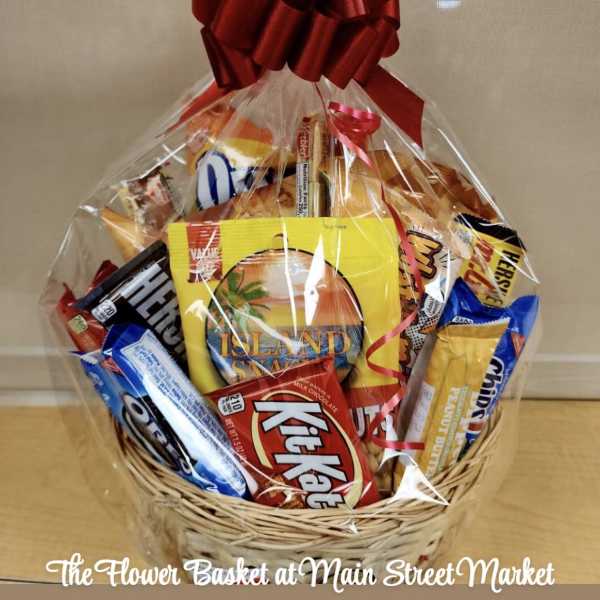 Gift basket of assorted snack bars and candy wrapped in clear cellophane with a red bow