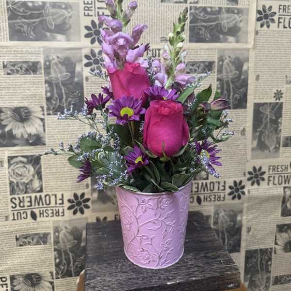 Pink roses and purple flowers arranged in a lavender metal pot
