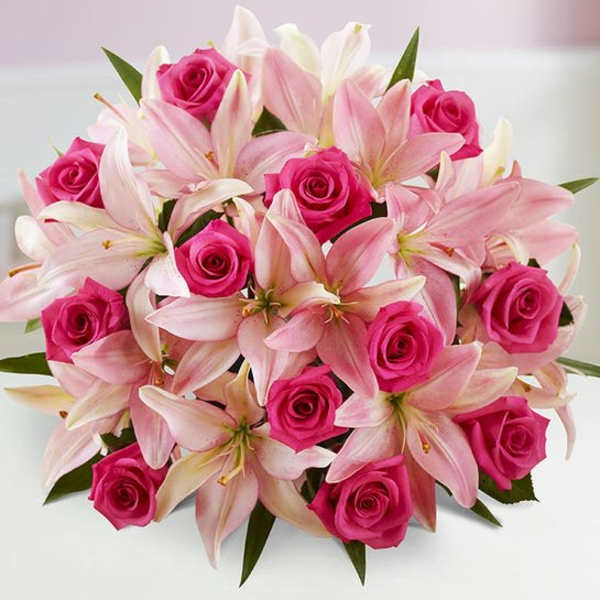 Pink roses and pale pink lilies arranged in a bouquet