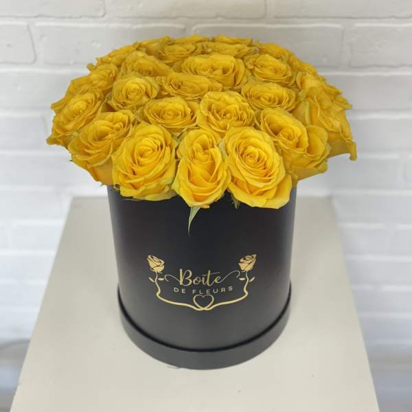 Yellow roses arranged in a black round box