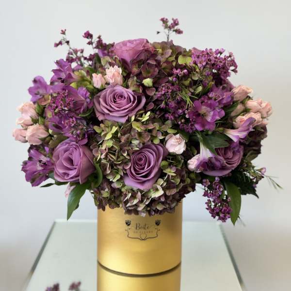 Purple and pink rose bouquet in a gold hatbox