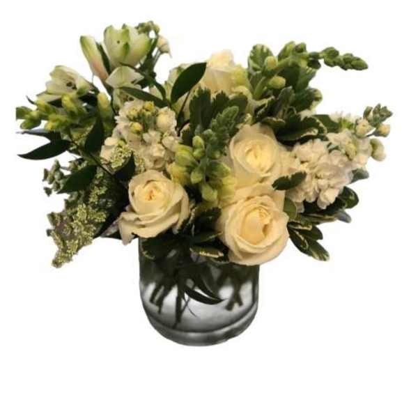 Cream roses and white flowers arranged in a glass vase