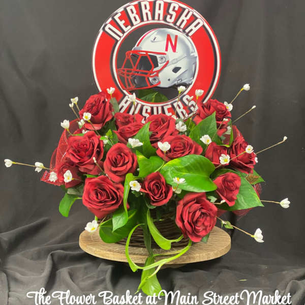 Red roses arranged with greenery and a Nebraska Huskers sign