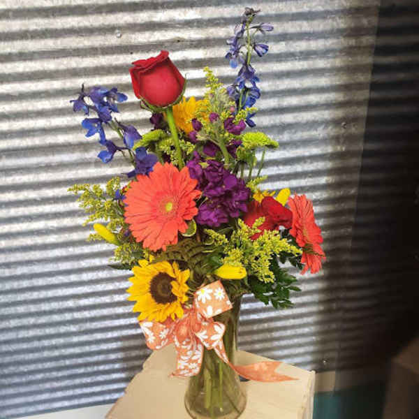 Colorful mixed bouquet in a glass vase with a ribbon