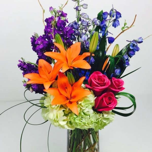 Colorful bouquet of lilies, roses, and hydrangeas in a glass vase