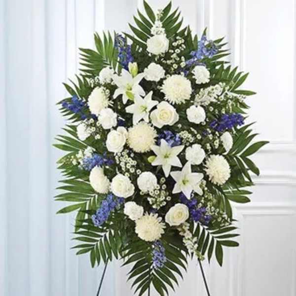 Standing funeral spray of white and blue flowers on an easel