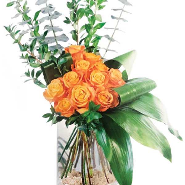 Orange roses in a clear vase with tall greenery