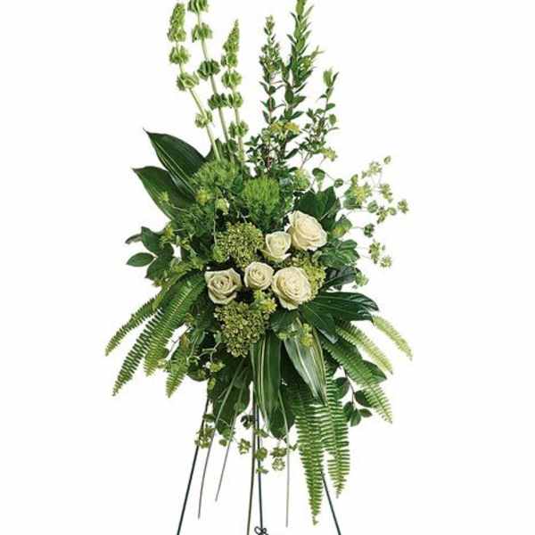 Tall standing floral spray with white roses and green foliage on a metal easel