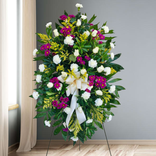 Standing floral wreath with white and magenta flowers and a white ribbon bow