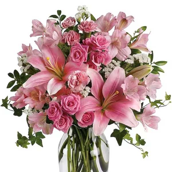 Pink lilies and roses arranged in a clear glass vase