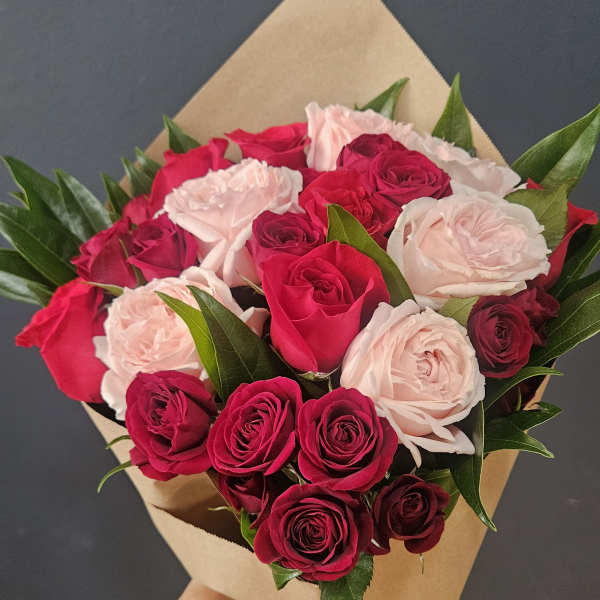 Bouquet of red and pale pink roses wrapped in kraft paper