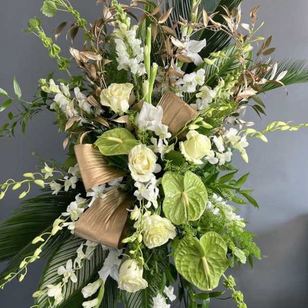 Tall floral spray with white roses, orchids, and tropical leaves