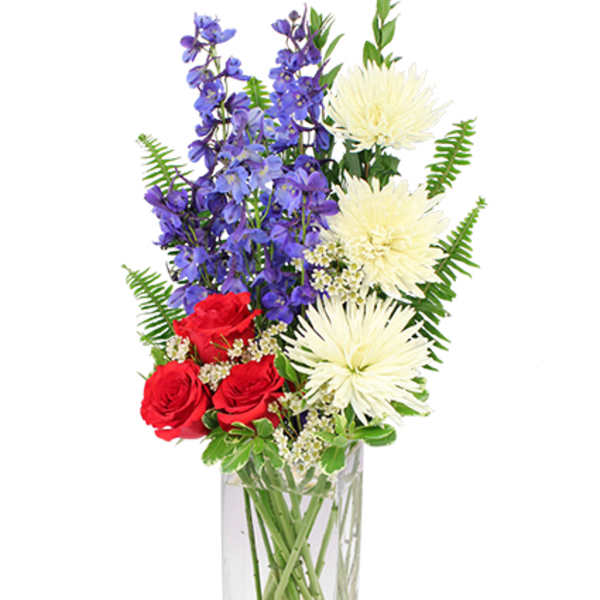 Red roses, purple flowers, and white blooms in a clear rectangular vase