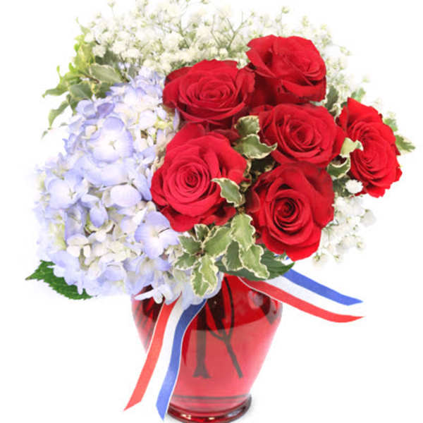 Red roses and pale blue hydrangeas in a red vase with ribbon