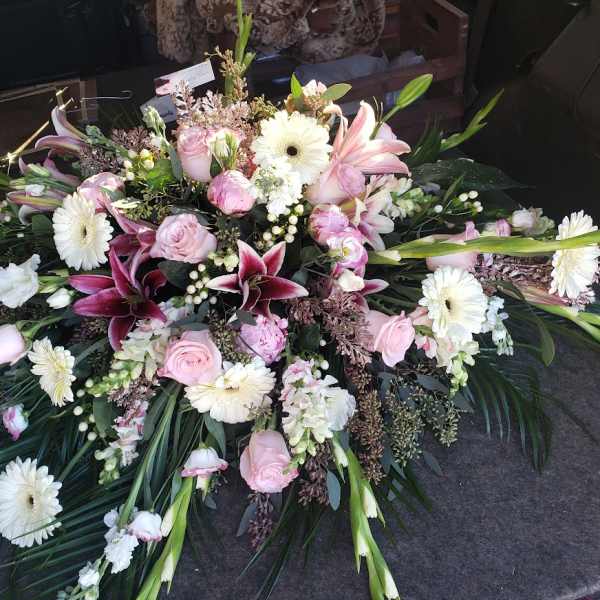 Large pink and white floral casket spray with lilies and daisies