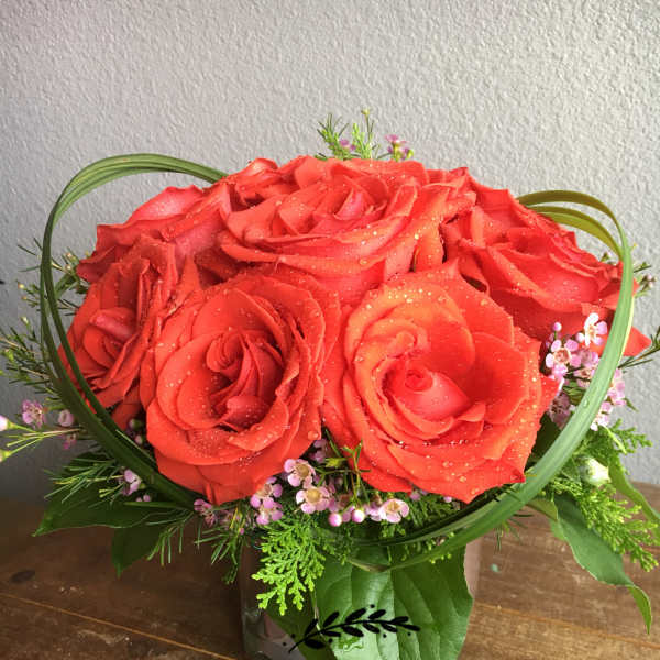Red rose bouquet with small pink filler flowers in a vase