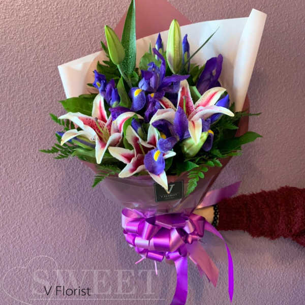 Bouquet of purple irises and pink-white lilies wrapped in paper