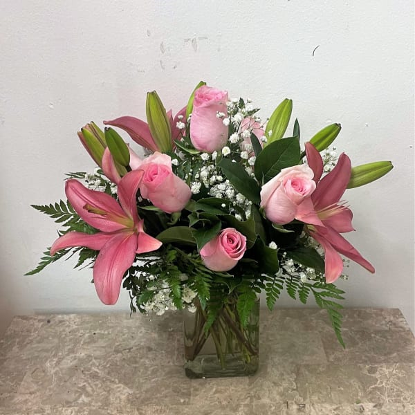 Pink roses and lilies arranged in a clear glass vase