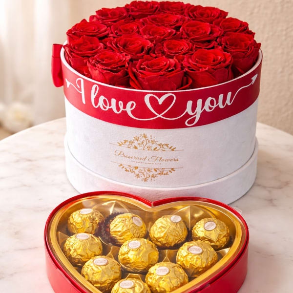 Red roses in a round box with a heart-shaped chocolate box in front