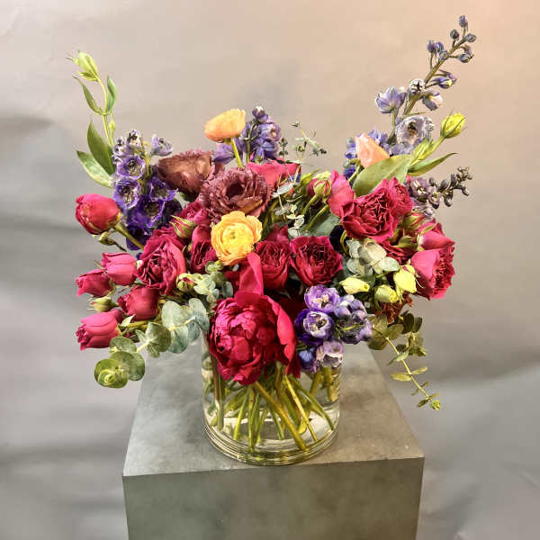 Mixed bouquet of pink, purple, and yellow flowers in a clear glass vase