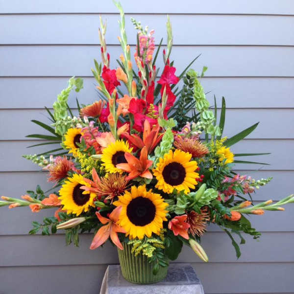 Bright mixed bouquet with sunflowers, orange lilies, and red gladiolus in a vase