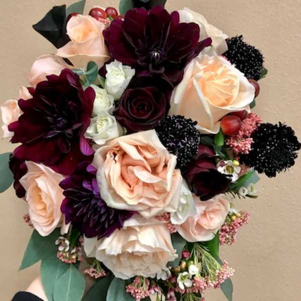 Bouquet of blush and burgundy roses with dark blooms and greenery