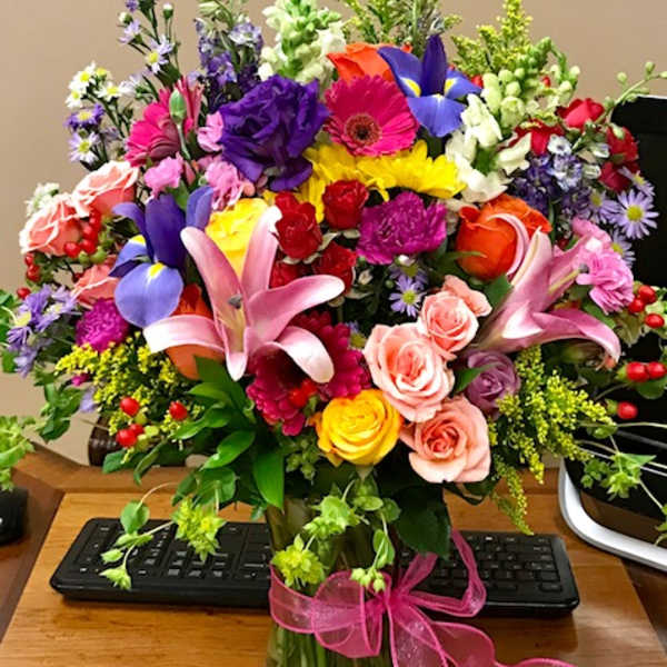 Colorful mixed bouquet in a glass vase with a pink ribbon