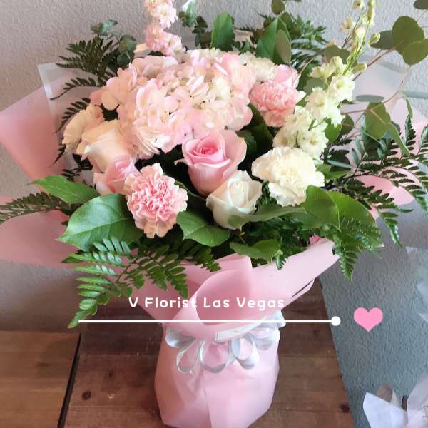 Pink and white bouquet with roses, hydrangea, and carnations in pink wrap
