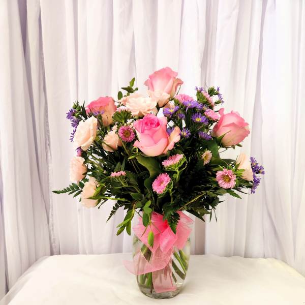 Pink and white roses with purple daisies in a glass vase