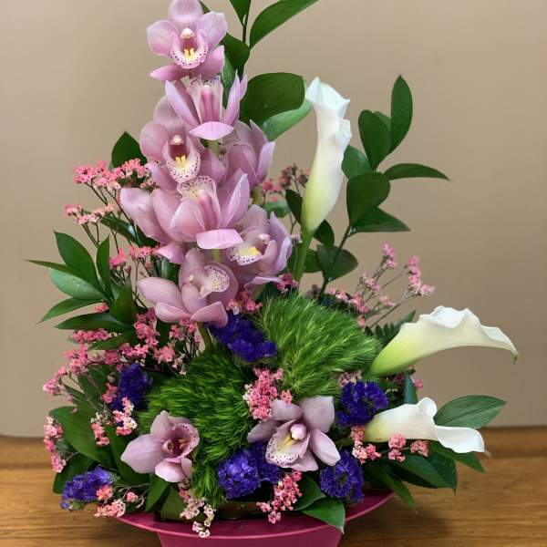 Pink orchids and white calla lilies in a magenta container
