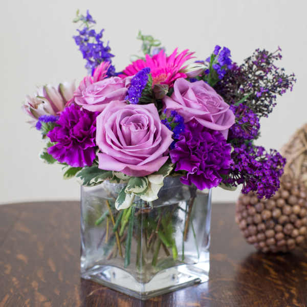Purple and pink flower arrangement in a clear glass vase
