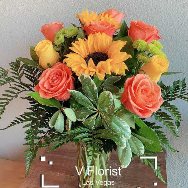 Vase arrangement with orange roses, yellow sunflower and yellow roses with green accents