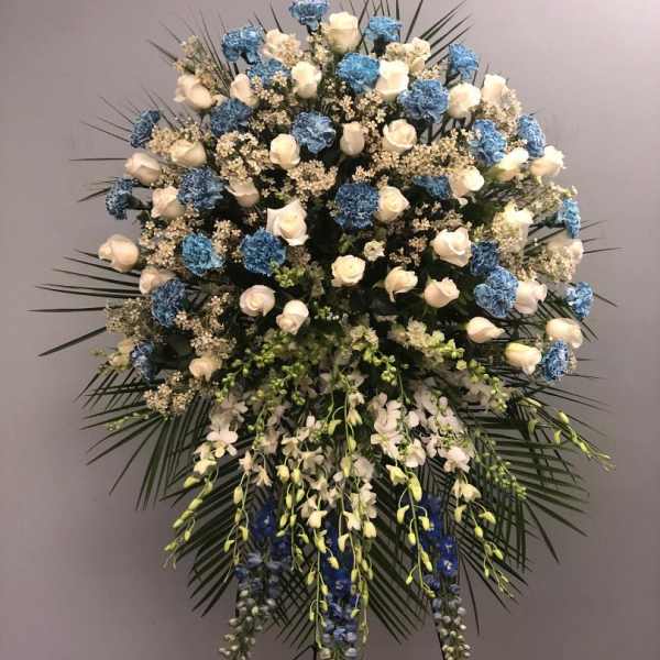 Large standing floral spray with white roses, blue carnations, and orchids