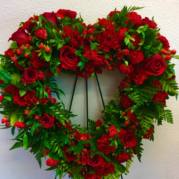 Heart-shaped wreath of red roses and carnations on a stand