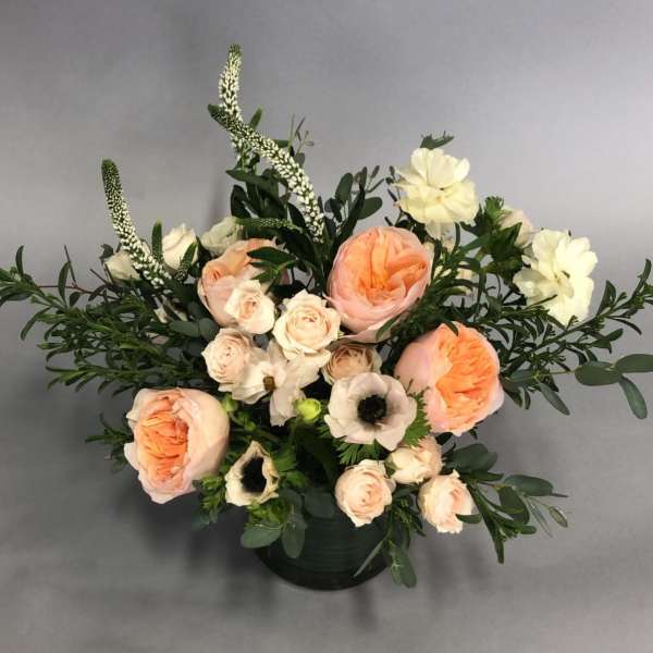 Peach and cream floral arrangement in a dark vase