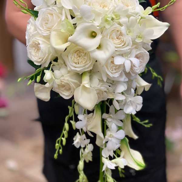 White bridal bouquet with roses, calla lilies, and trailing orchids