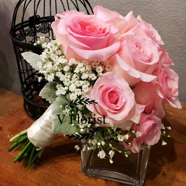 Pink rose bouquet with white filler flowers in a glass vase
