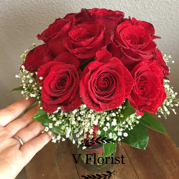 Bouquet of red roses with baby's breath in a glass vase