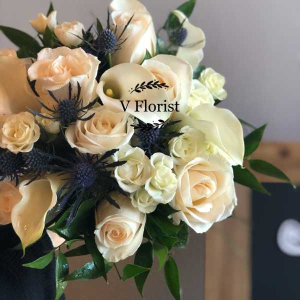 Bouquet of cream roses, white calla lilies, and blue thistle