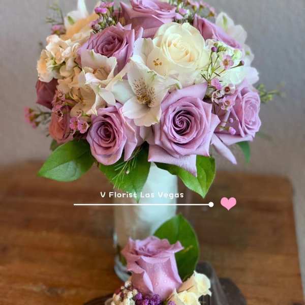 Lavender and white rose bouquet in a glass vase with a ribboned rose corsage below