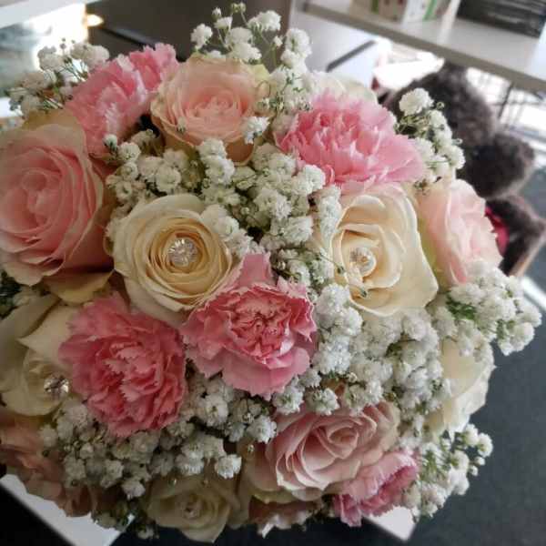 Round bouquet of pink and cream roses with white filler flowers